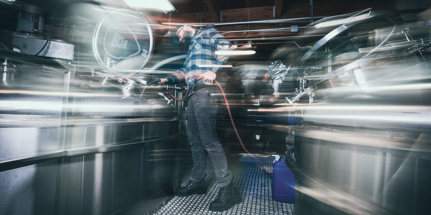 Person using a pressure washer in a high-traffic indoor setting with motion blur effect.
