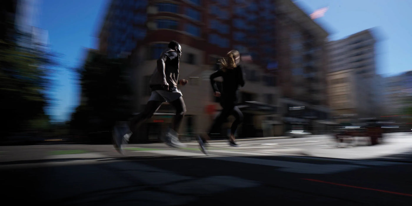 Two people running on a city street with blurred motion