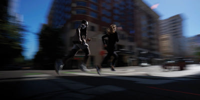 Two people running on a city street with blurred motion