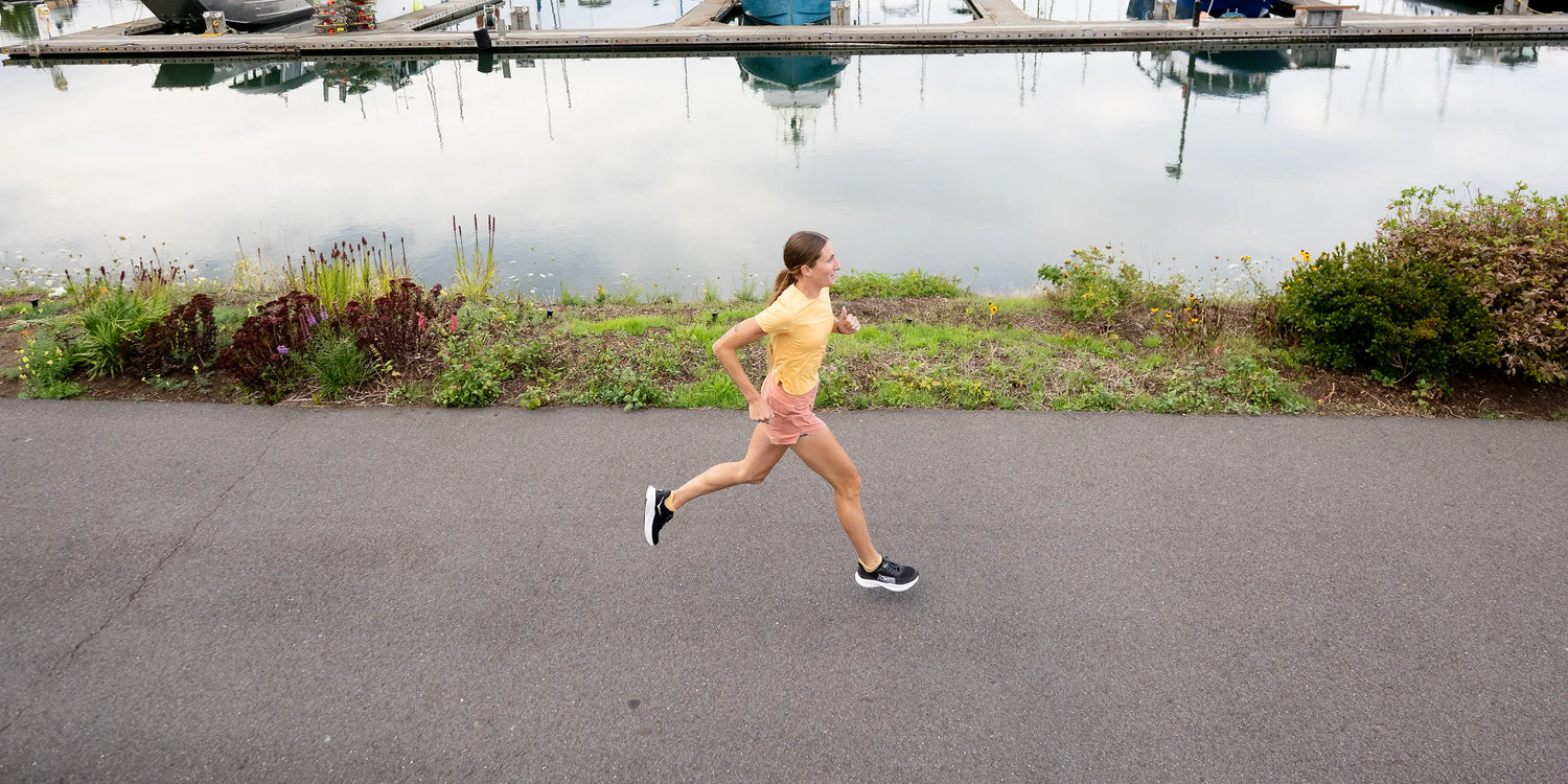 Woman Running on sidewalk next to a body of water while wearing Superfeet insoles.