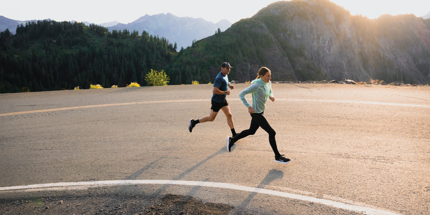 Two people running up and incline on a road