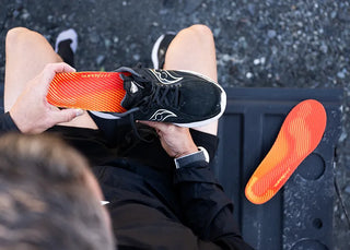 Person inserting Superfeet insole into running shoe for enhanced comfort and support before a workout.