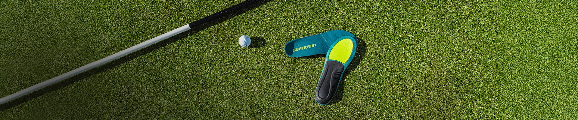 Superfeet Insoles against putting green with a golf ball & golf putter in the background. 