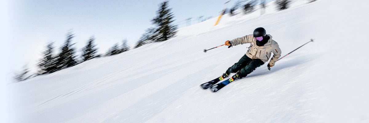 Person skiing down a snowy slope with trees in the background.