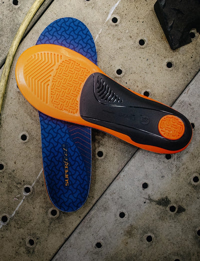 Superfeet's Work Cushion Insole against a grey background with tools and cables laying nearby. 