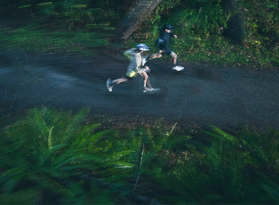 Two runners on a path in a wooded area at night. 