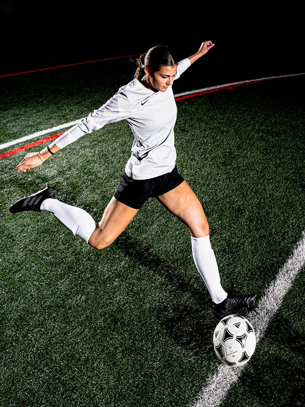 Soccer player in action on a field with a dark background