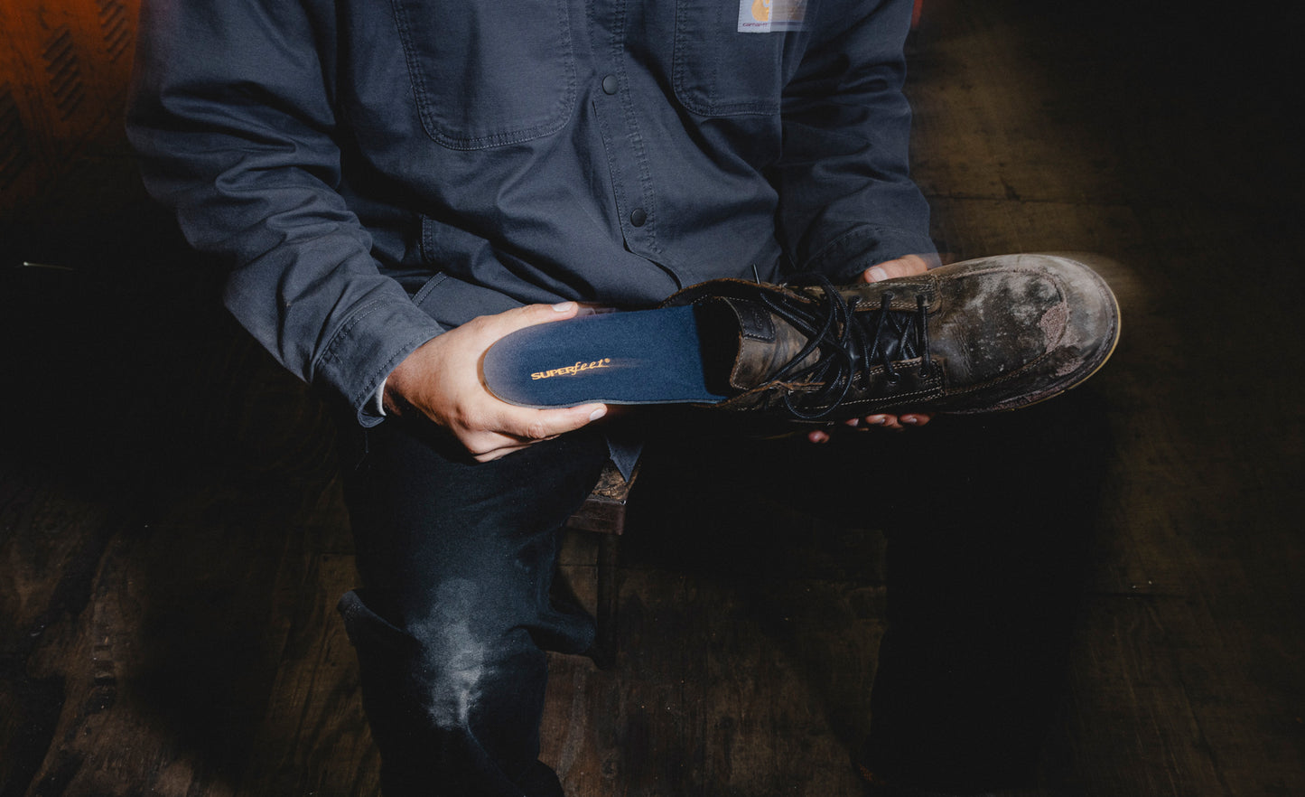 Person holding a black work shoe while inserting Superfeet's Work Memory Insole into the show. 
