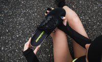 Person holding a black sneaker with a Superfeet's Run Pace Insole inside of the sneaker. 