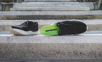 Superfeet's Run Pacer Elite insole sticking out of a black athletic shoe outside.
