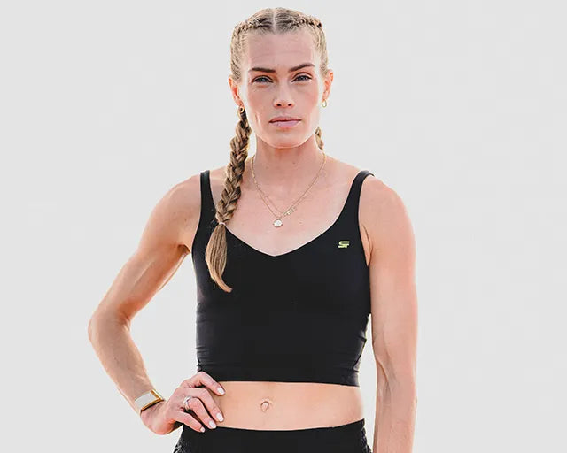 Woman wearing a black sports bra and leggings on a light gray background
