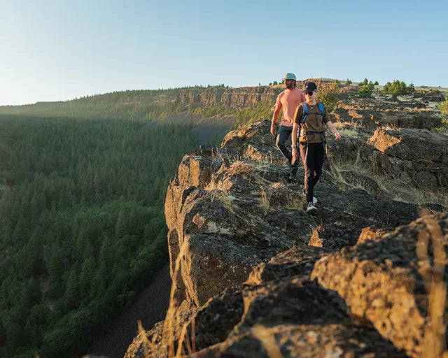 Two hikers walking along a rocky ridge at sunset, supported by Superfeet insoles for comfort and stability.