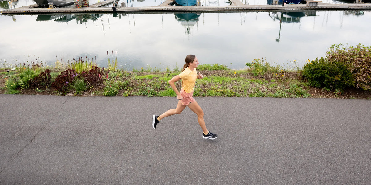 Woman Running on sidewalk next to a body of water while wearing Superfeet insoles. 
