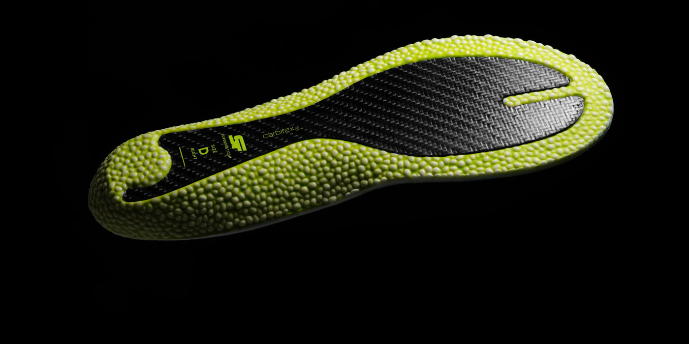 The bottom of a Superfeet Run Pacer Elite insole with Superfeet branding and Carbitex plate on a dark background