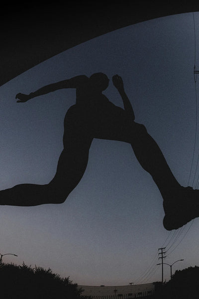 Silhouette of a person jumping against a dark night sky with power lines and buildings in the background