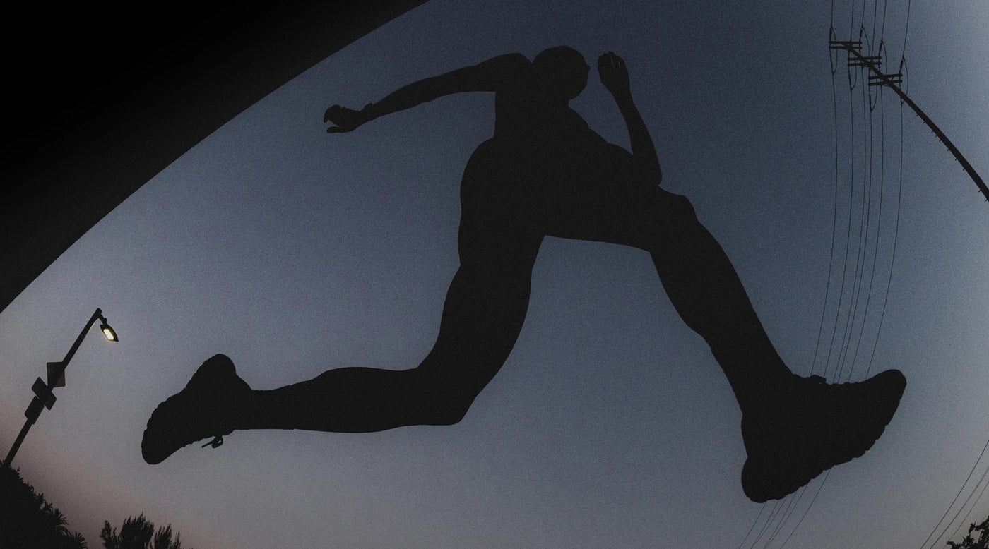 Silhouette of a person running against a dark night sky with power lines above