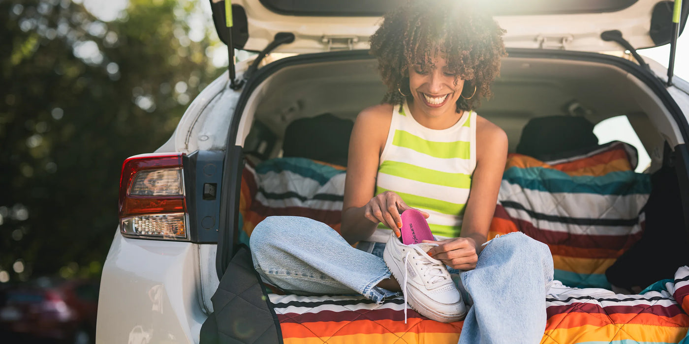 Women sitting in back of car inserting a Superfeet insole into her walking shoe.