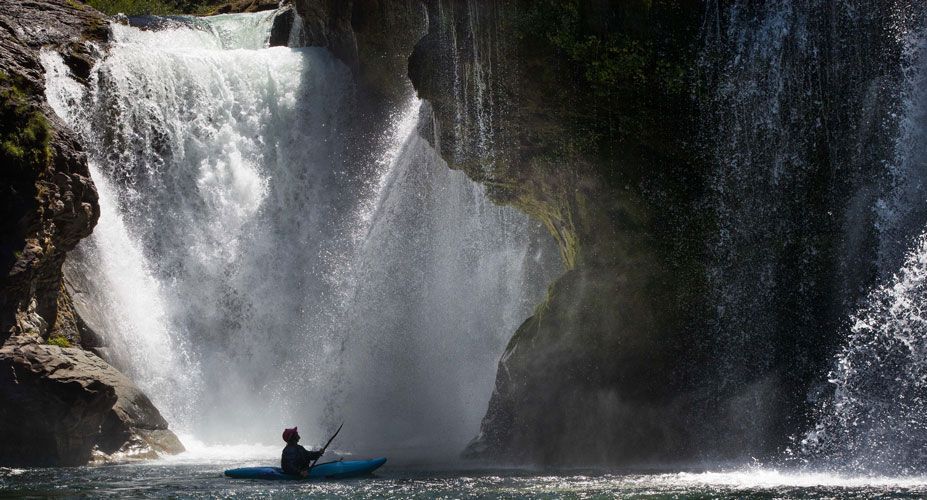 Kayaker under a large waterfall