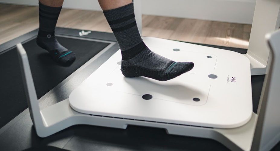 Feet with black socks step onto Volumental scanner