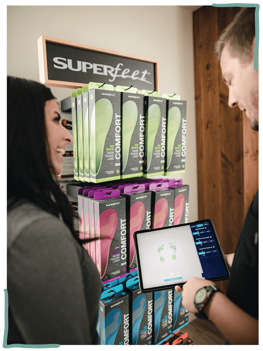 A shopper reviewing results from 3D foot scan on a smart tablet with sales associate 