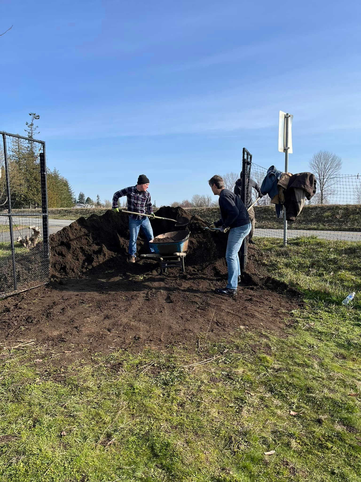 Two Superfeet volunteers shovel garden dirt during a work project at the Ferndale Community Garden