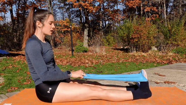 Woman demostrating toe exensions with a band, sitting on an orange exercise mat