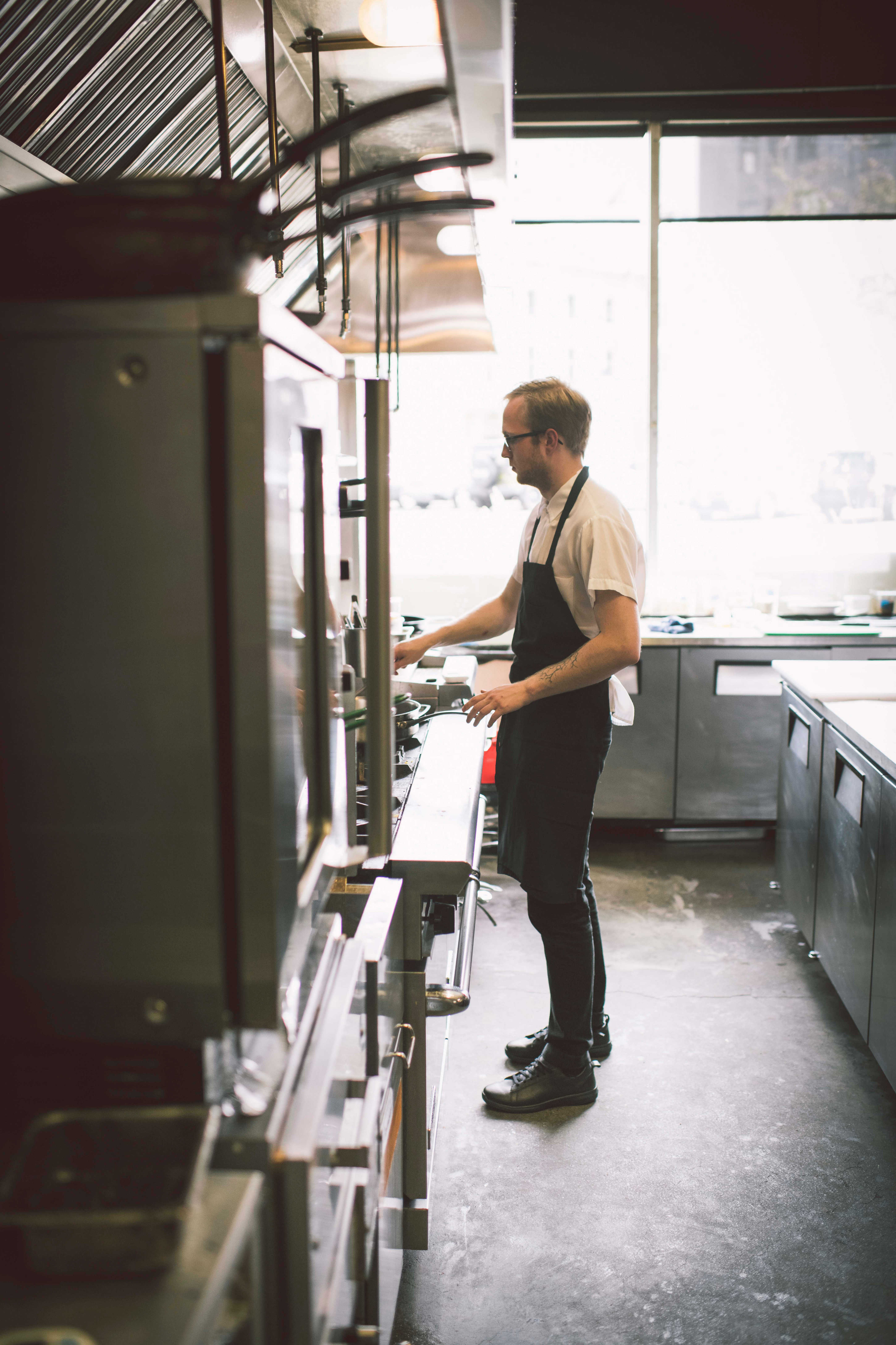 A chef stands at a commercial stove in the kitchen of a restaurants
