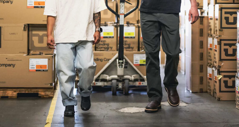 Waist down image of two people walking in a warehouse